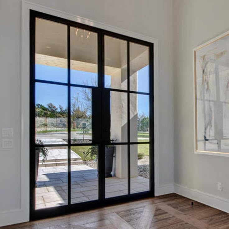 Large glass double doors with black metal frames open to a sunny patio with tile flooring. For expert commercial glass door repair in Pinellas County, FL, keep your space both stylish and secure year-round.