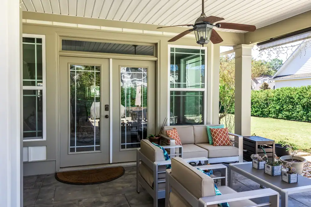 Crystal clear glass door with side panels, stylish outdoor seating on covered porch, perfect for home improvement, window repair, and glass door replacement by Same Day Glass Repairs.