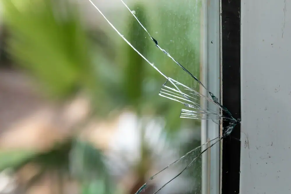 Shattered glass window with cracks and broken panes, illustrating the need for emergency glass repair services. Ideal for showcasing prompt and professional glass repair solutions for homes and businesses.