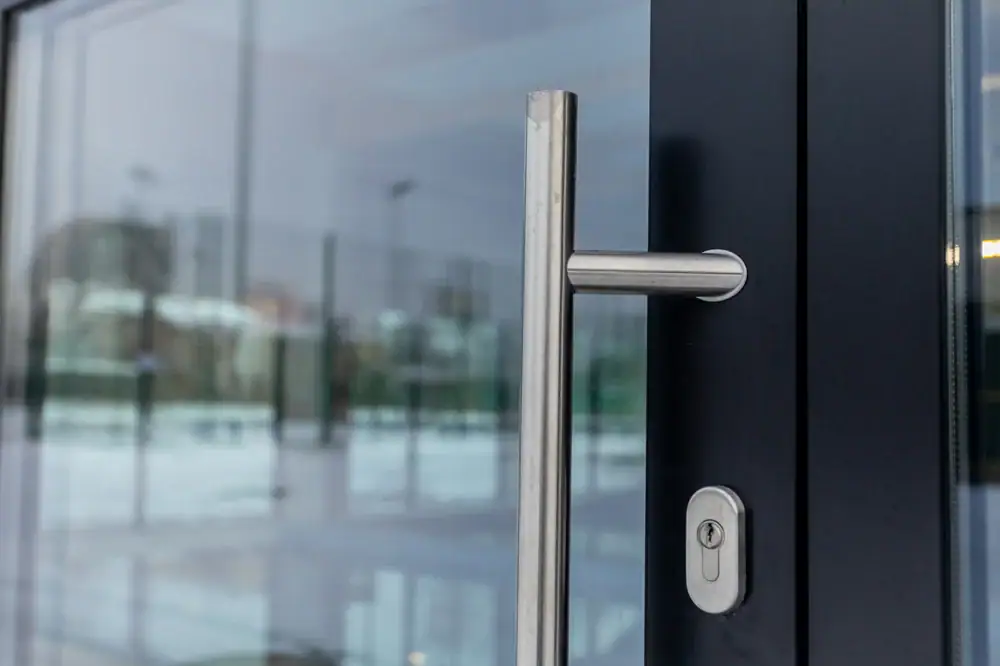 Stainless steel door handle and lock on glass door, commercial glass repair and replacement, professional glass services.